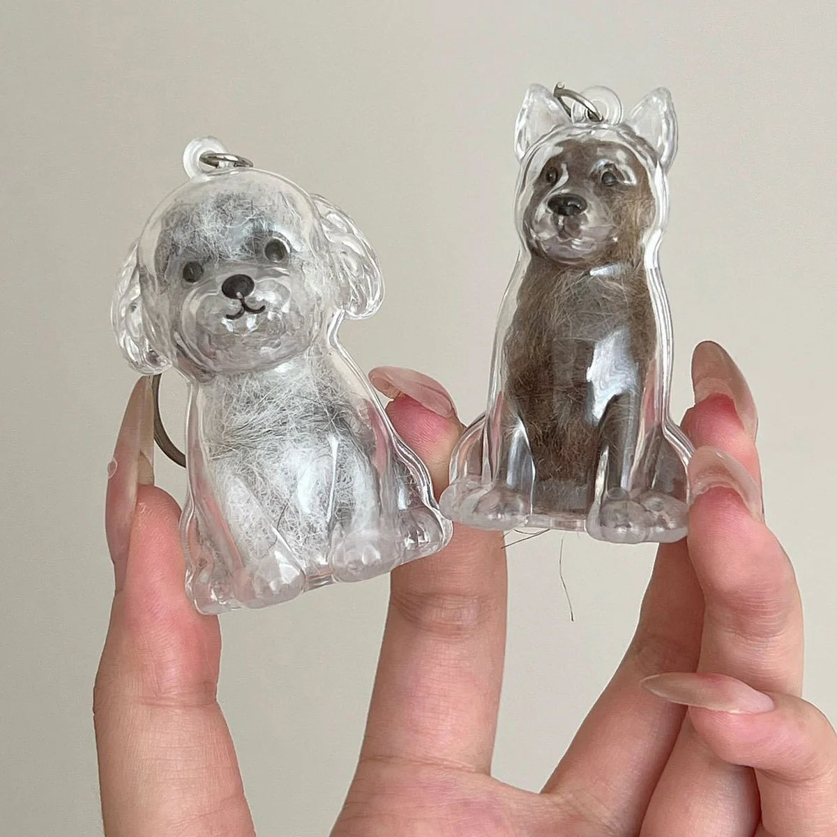 A clear resin keychain featuring a dog design, showing both a light gray and a dark brown puppy figure.