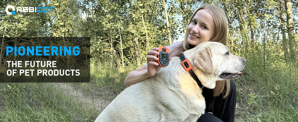 A woman holds a light-colored dog while wearing an orange remote training collar.
