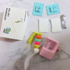 An automatic electric hanging cat toy with a cord and a pink plastic component is shown on a white marble surface.
