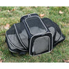 Black expandable pet carrier backpack with mesh openings and reflective trim placed on green grass.