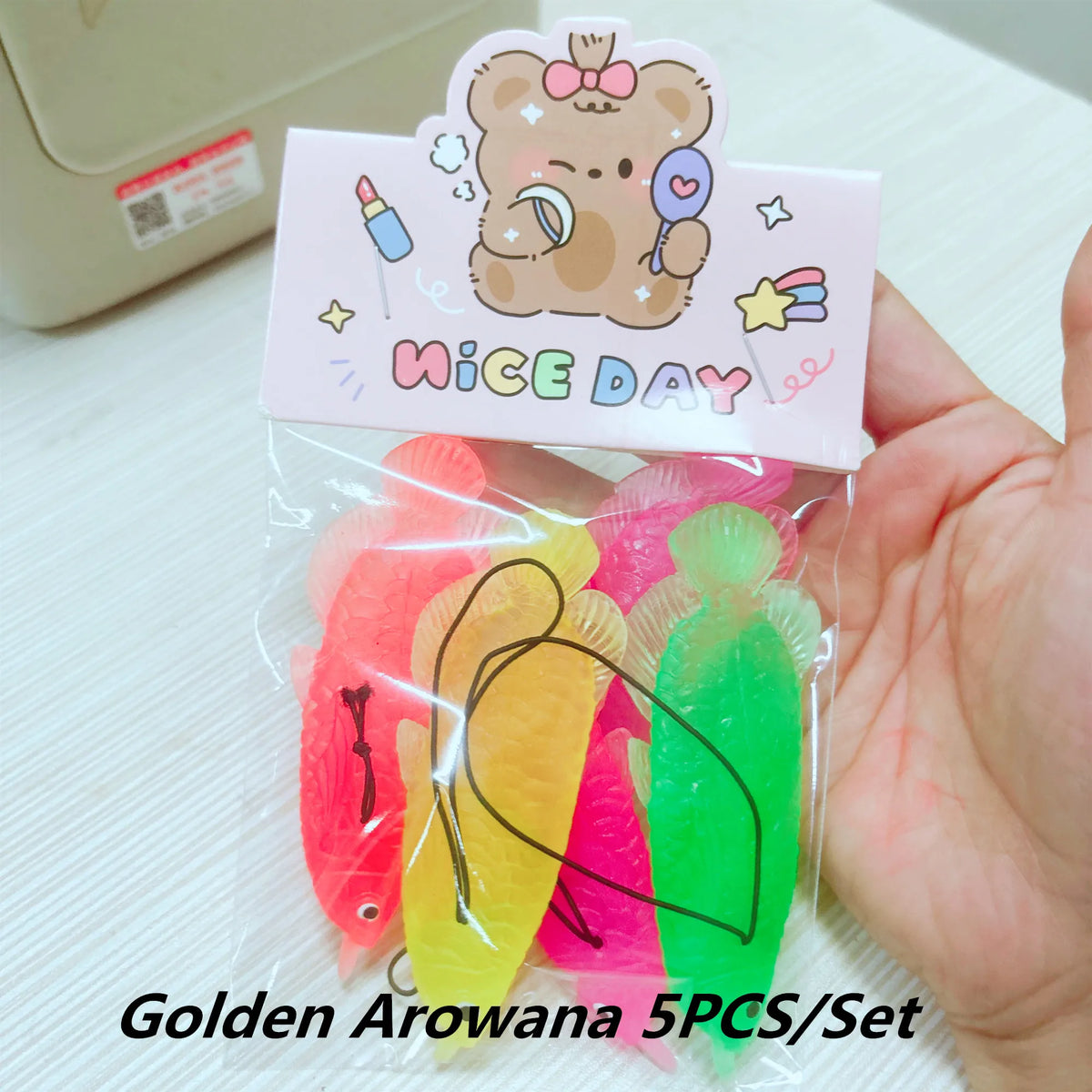 A set of five golden arrowana goldfish bath toys in various colors packaged in a clear plastic bag.