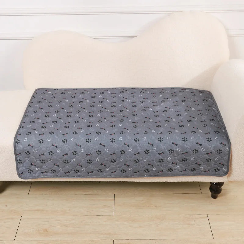 Alfombrilla desechable para mascotas gris colocada sobre una superficie tapizada color crema.