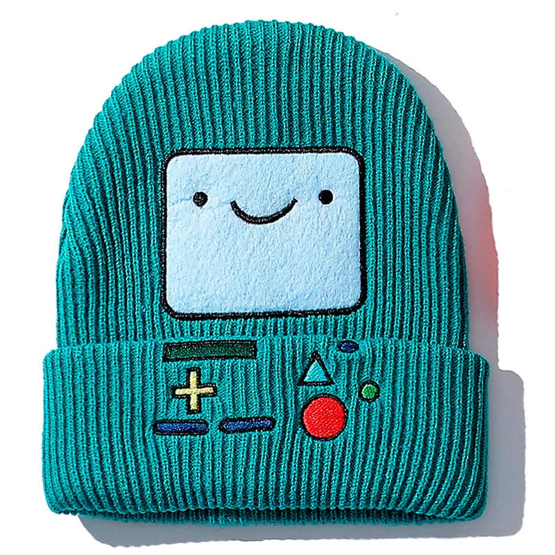 A teal knitted beanie hat featuring a square face design embroidered on the front.