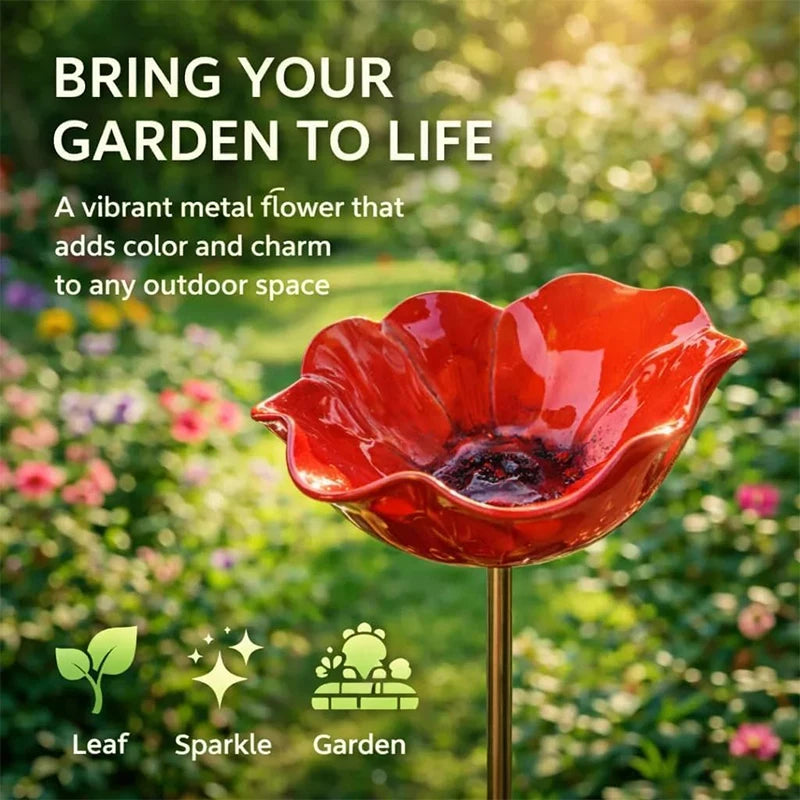 A vibrant red flower-shaped outdoor bird bath with a gold stand, set in a lush green garden.
