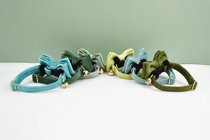 A set of elegant velvet cat collars in shades of teal, olive green, and blue-gray with adjustable buckles.