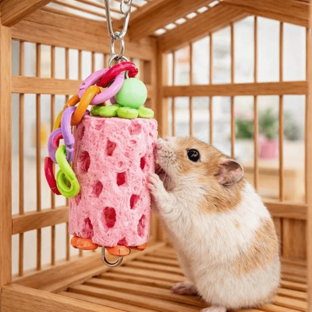 A small brown pet is interacting with a pink, textured hanging chew toy inside a wooden cage.