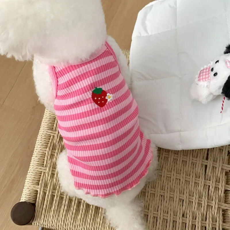 Pink-weiß gestreiftes Kühlvest für Hunde neben einem weißen gesteppten Kissen.