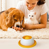 A woman is gently petting a dog and a kitten on a beige mat with an orange interactive licking mat.