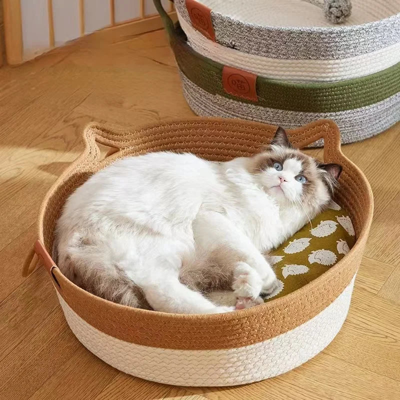 A fluffy white and gray cat is relaxing in a handwoven rattan cat bed with a cotton rope edge.