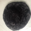 A round, black plush pet bed with a fluffy texture and anti-slip base.