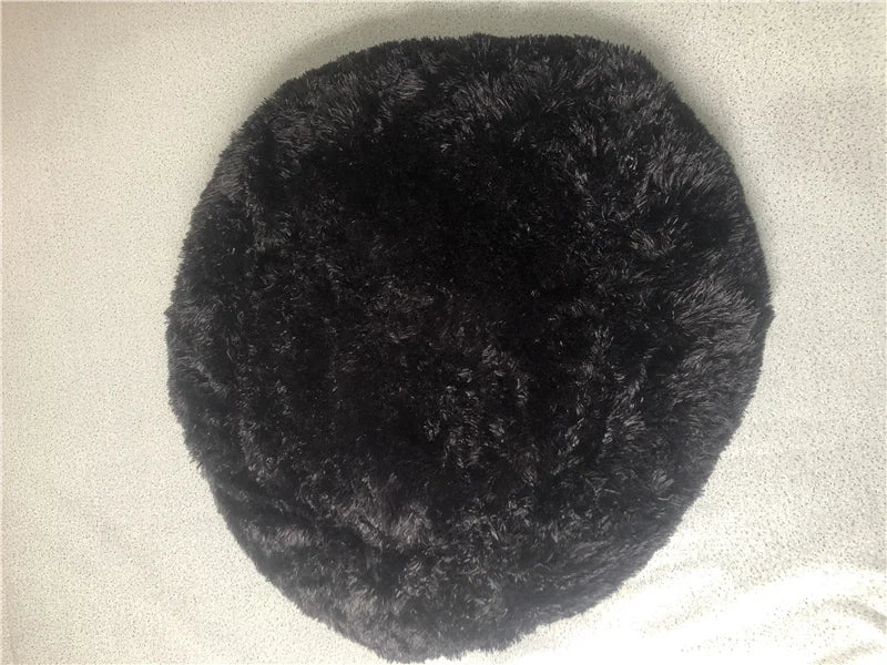 A round, black plush pet bed with a fluffy texture and anti-slip base.