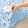 A hand is interacting with a white, motion-activated squeaky mouse toy on a blue patterned fabric.