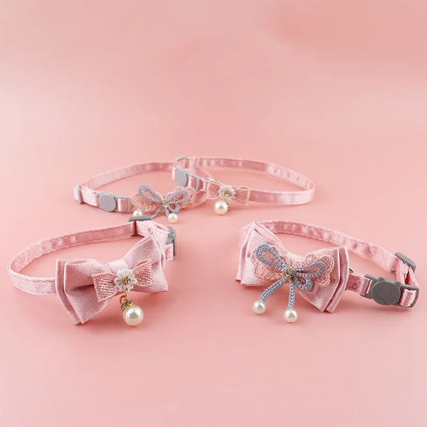 Pink lace bow cat collar with a bell and bead charm displayed on a pink background.