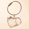 A clear glass charm shaped like a cat is attached to a braided gold-colored keychain ring.