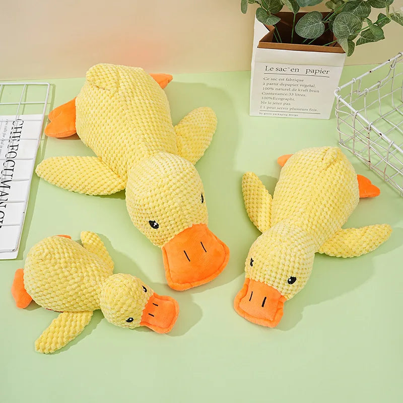 A collection of yellow and orange knitted duck plush toys displayed on a light green surface.