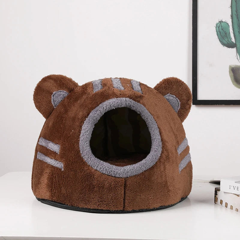 Plüschiger brauner Bärenkopf Katzenbett mit grauen Streifen, auf einer weißen Oberfläche.