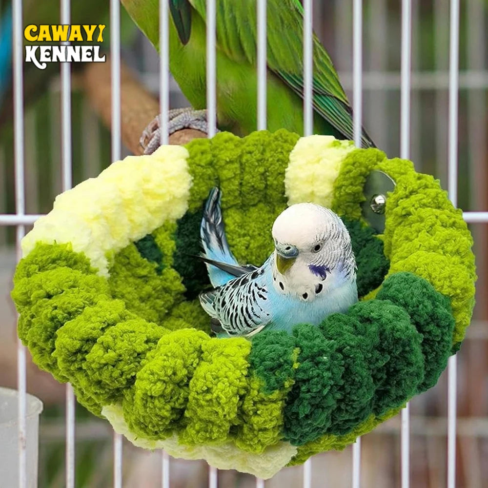 A small blue bird is perched inside a round, green plush nest bed.