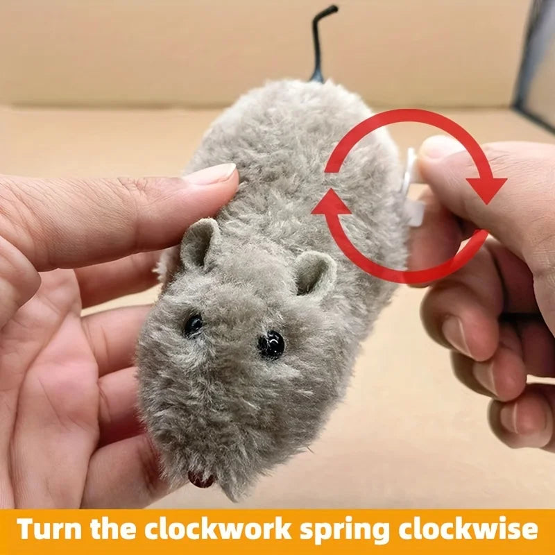 A hand is turning a gray wind-up plush mouse toy clockwise to operate it.