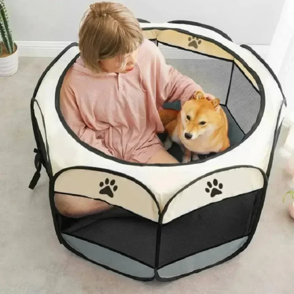 A person is sitting inside a portable foldable pet tent and playpen with a dog looking out.