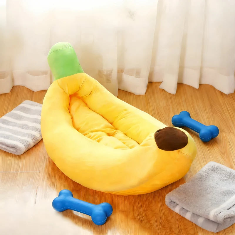 Un lit d'animal en forme de banane jaune pour chats et chiens, posé sur un plancher en bois avec des serviettes grises à prox