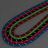 A close-up of a reflective nylon dog leash featuring multiple colored stripes including red, green, black, and blue.