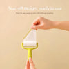 A hand is using a yellow mini lint roller with white adhesive paper to tear off a piece.