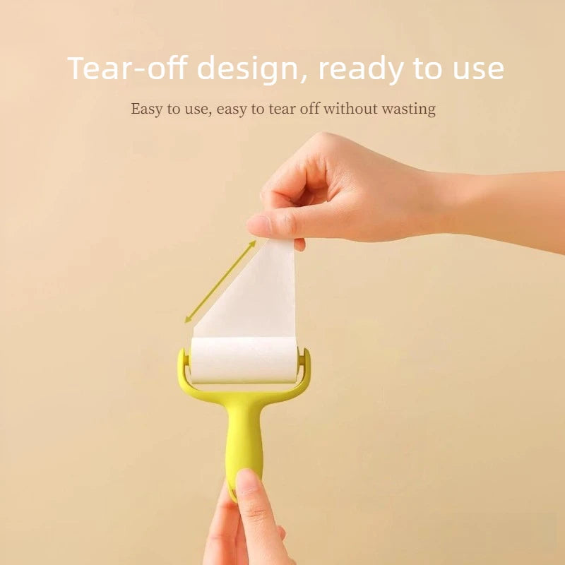 A hand is using a yellow mini lint roller with white adhesive paper to tear off a piece.