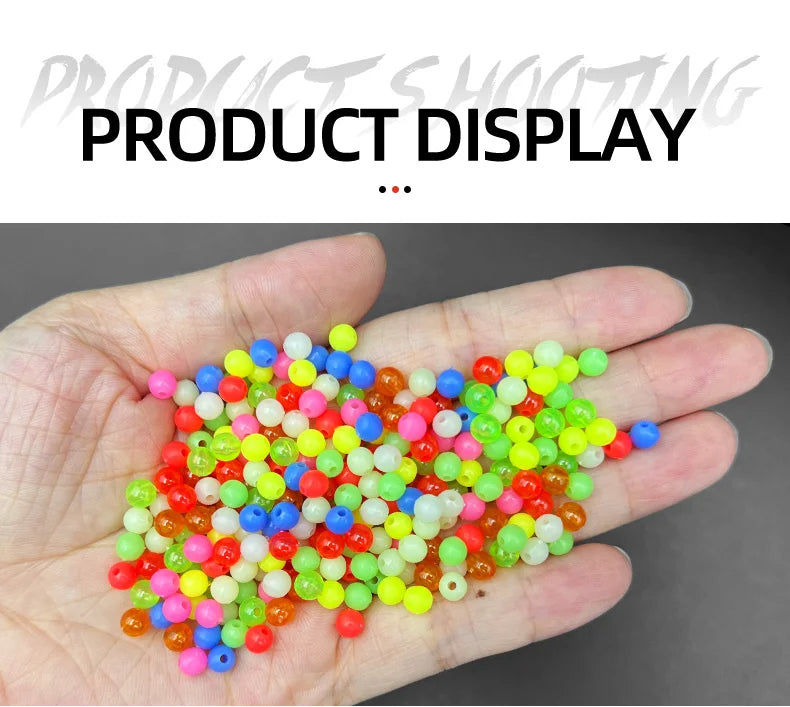 A hand holds a pile of mixed glow-in-the-dark fishing beads in various bright colors.