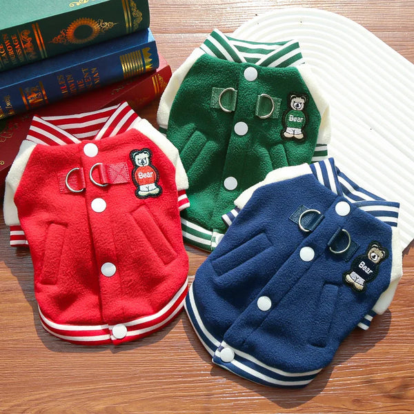 A collection of three fleece dog jackets in red, green, and navy blue with D-rings and bear patches.