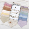 A collection of nine cotton baby bibs in various pastel shades and printed designs laid out on a white surface.
