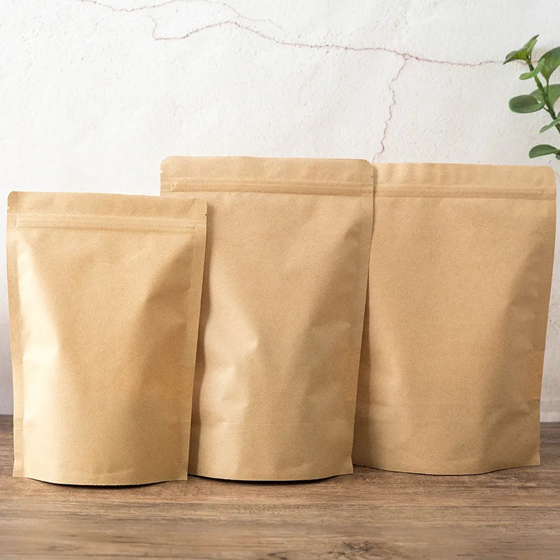 Drei beige wiederverwendbare Kraftpapier-Zip-Beutel stehen auf einer Holzoberfläche.