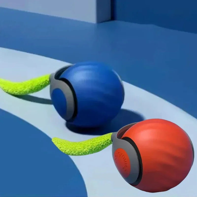 Pelota de juguete interactiva para gato azul y naranja con apéndices peludos verdes sobre una superficie azul.