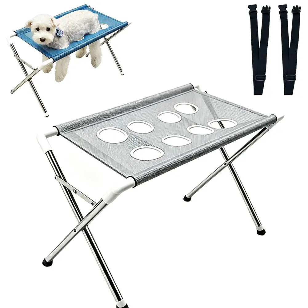 A silver pet grooming stand with a mesh hammock for bathing and nail trimming, shown alongside a small dog.