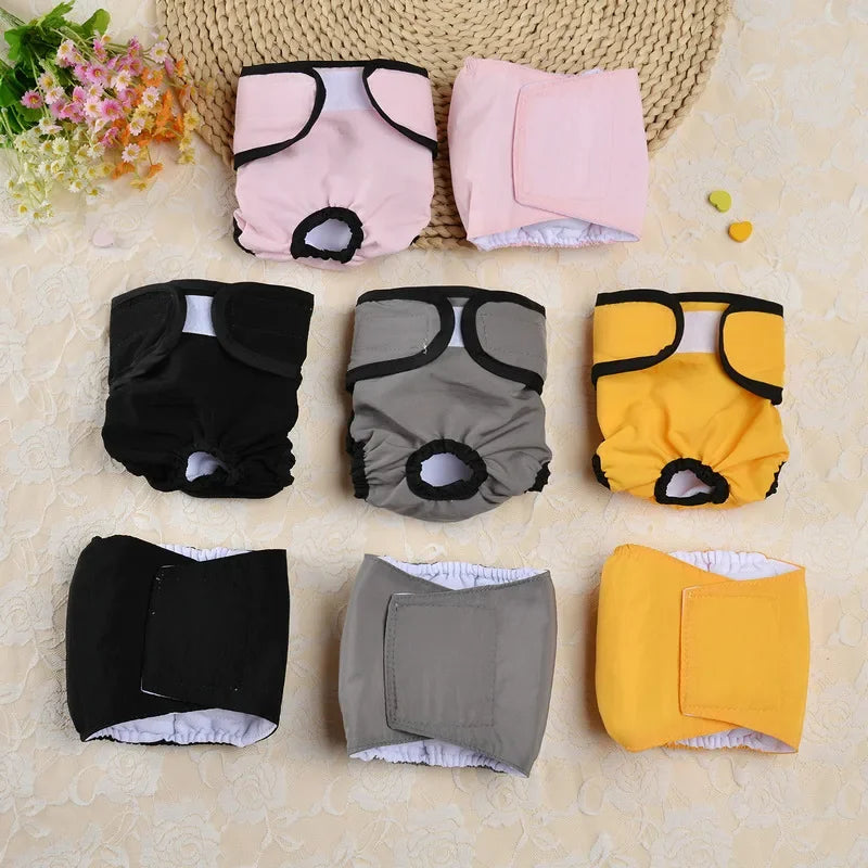 Un ensemble de couches réutilisables pour chiens de couleur rose, noir, gris et jaune avec ajustements.