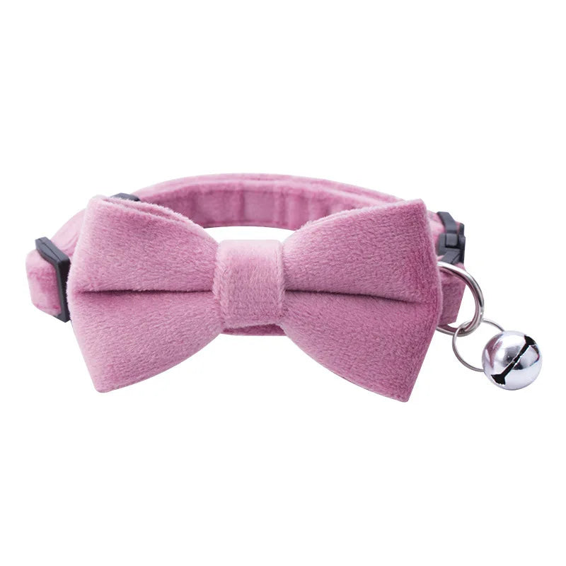 A pink adjustable breakaway cat collar featuring a bow tie and a silver bell.