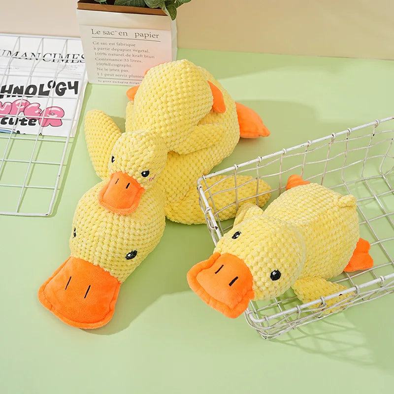 Yellow knitted plush duck toys in various shapes and sizes displayed in a wire basket.