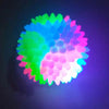 A glowing rubber fetch ball for dogs with vibrant neon green, blue, and pink light emanating from its surface.