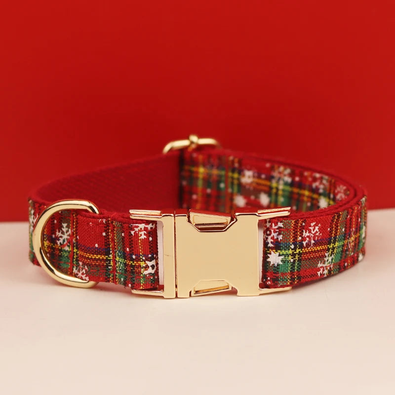 A red plaid dog collar with a gold buckle resting on a white surface.