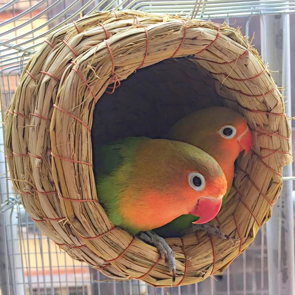 A small, handmade natural straw bird nest with a circular entrance, viewed from the front.