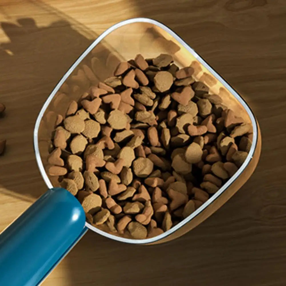 A clear measuring scoop filled with brown, heart-shaped pet food pellets.