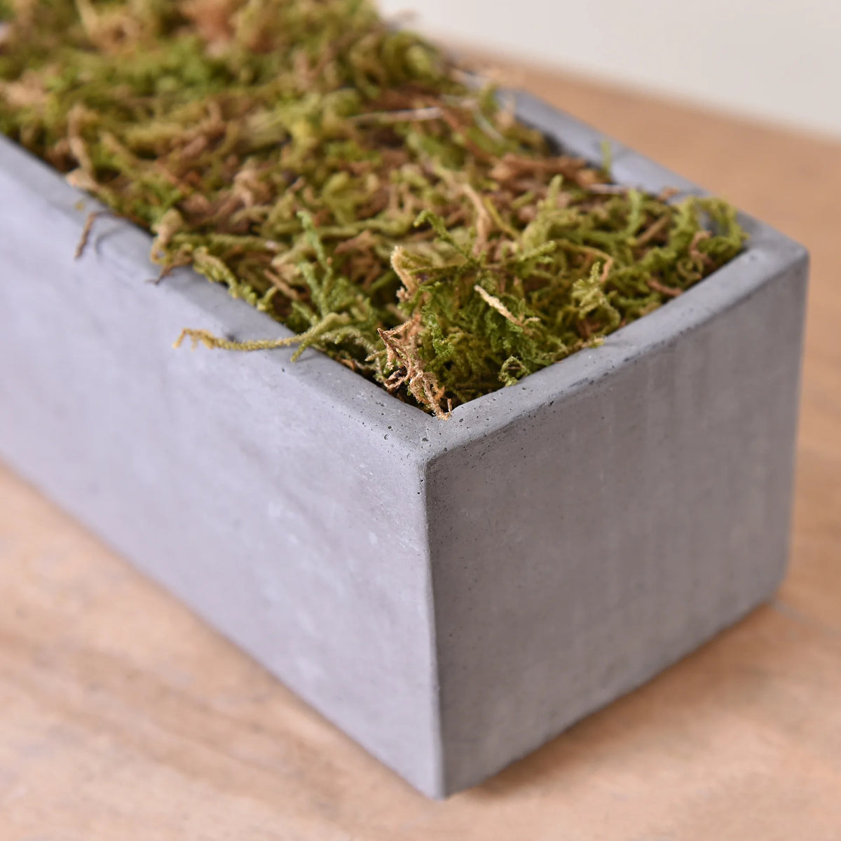 A rectangular gray container filled with green artificial moss for crafts and decor.