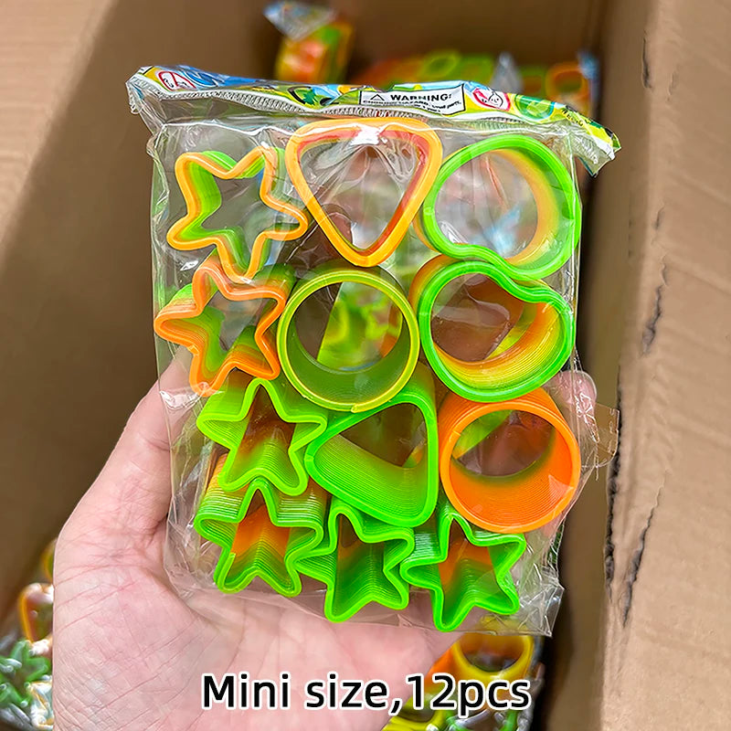 A hand holds a clear plastic bag containing 12 colorful spring coil toys in various shapes and colors.