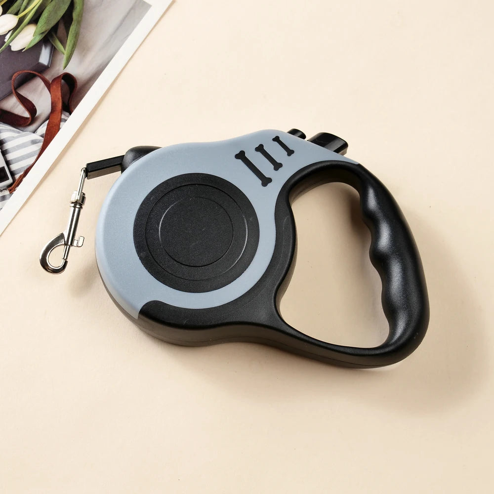 A gray and black retractable dog leash with a black handle is shown on a light background.