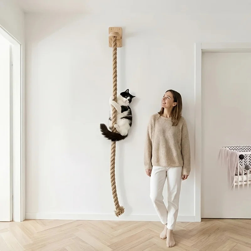Eine Frau steht neben einer weißen Katze, die an einem Wand-Kratzbaum aus Sisal hängt.