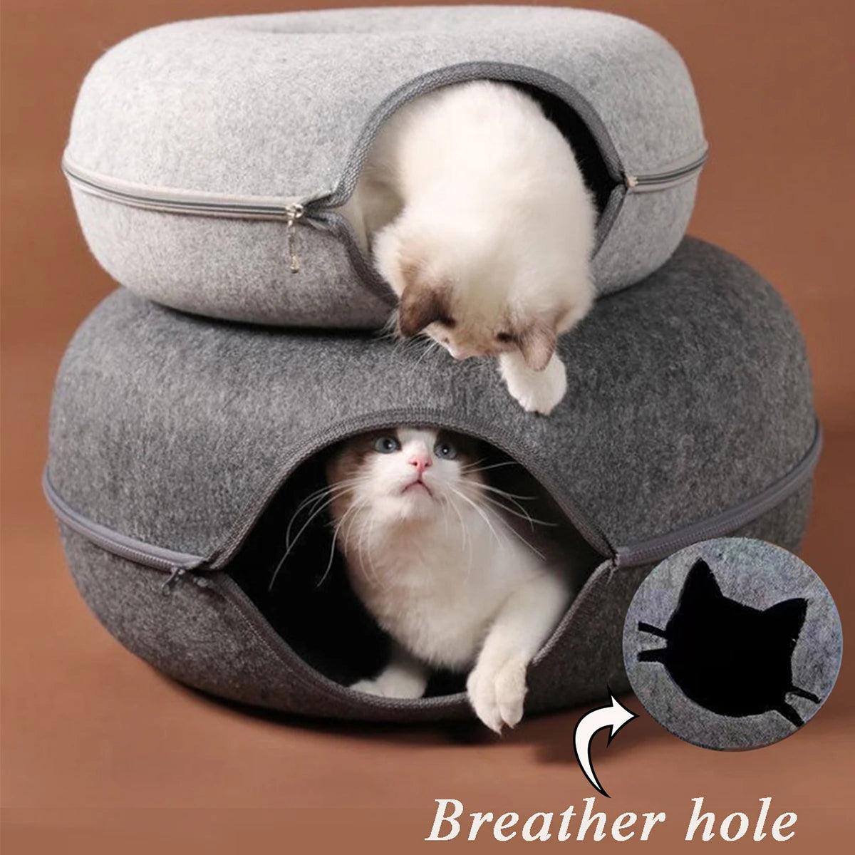 A fluffy white kitten is visible inside a gray fabric tunnel cat bed, showing the breather hole.