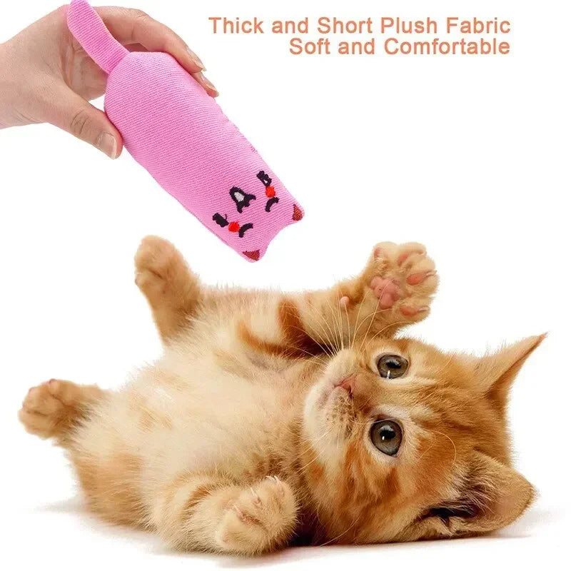 A small orange kitten is lying down next to a pink plush fabric toy.