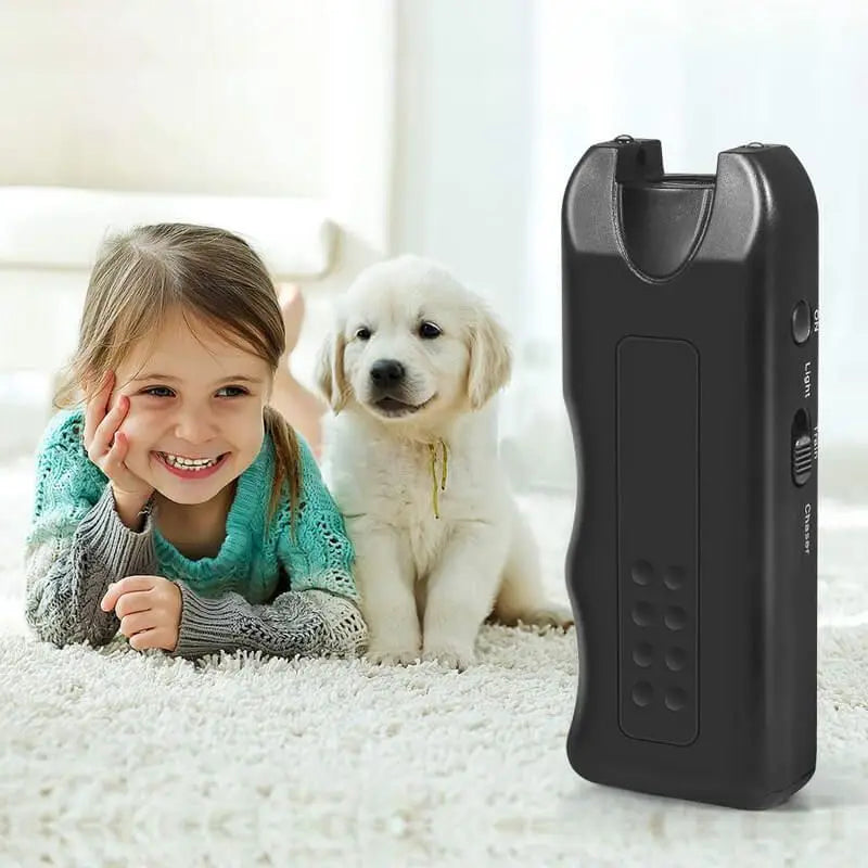 Disuasorio ultrasónico para perros negro con linterna LED, junto a una niña sonriente y un golden retriever.
