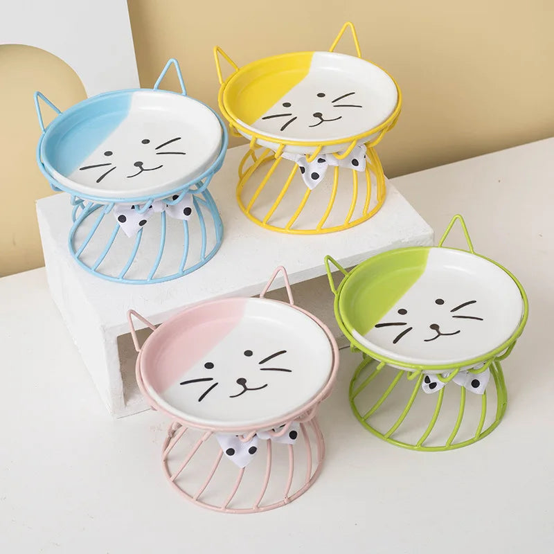 A set of three elevated ceramic cat food dishes with non-slip wire stands in yellow, blue, and pink.