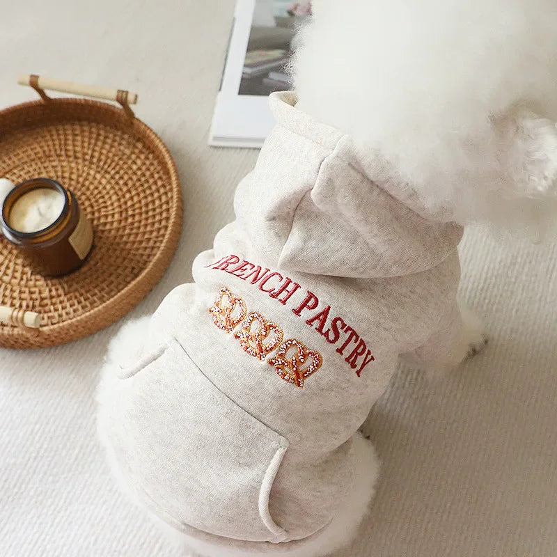 A light beige embroidered hoodie with a fluffy white hood for a small dog