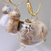 A set of ceramic cat charms with gold-colored chains and clasps, featuring various orange and white tabby cats.